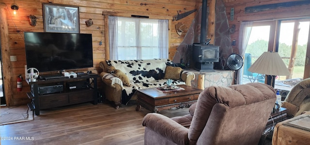 living room with a wood stove, wood walls, and hardwood / wood-style floors