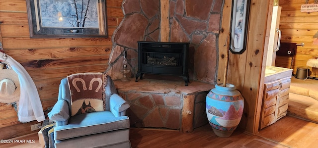 living area with a wood stove and wood-type flooring