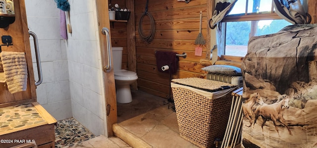 bathroom with a shower, toilet, and wood walls