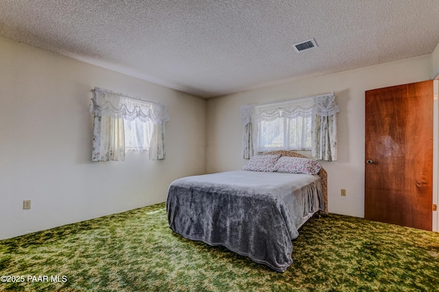 carpeted bedroom with a textured ceiling and visible vents