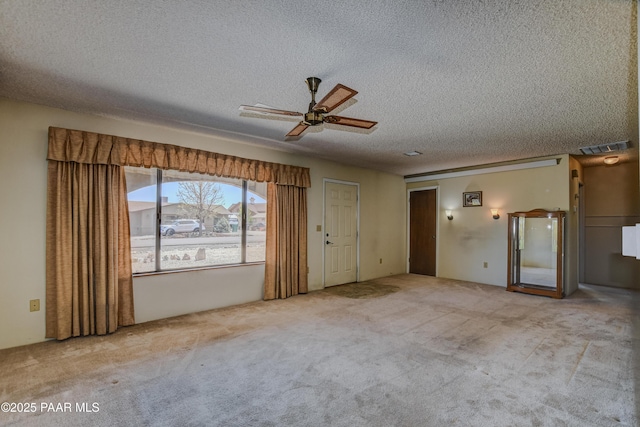 carpeted spare room featuring ceiling fan, a textured ceiling, and visible vents