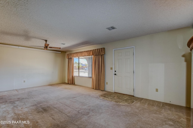 carpeted spare room with a ceiling fan, a textured ceiling, and visible vents