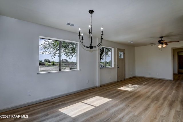 unfurnished dining area with hardwood / wood-style flooring and ceiling fan with notable chandelier