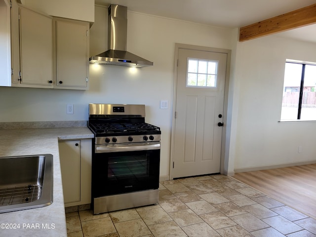 kitchen featuring sink, a healthy amount of sunlight, wall chimney range hood, and stainless steel range with gas stovetop