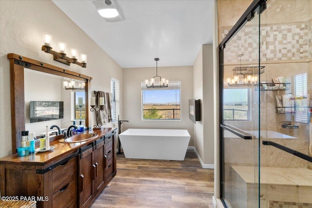 1445 S Table Mountain Rd, Chino Valley, AZ 86323 - bathroom with a chandelier, wood finished floors, vanity, a freestanding tub, and a shower stall