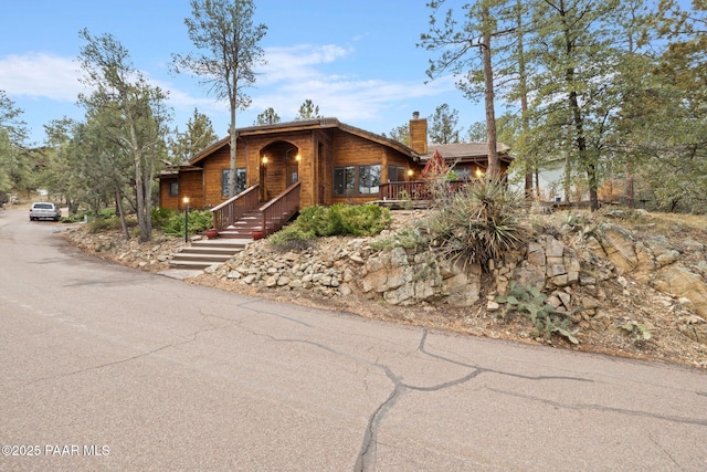 rustic home with driveway and a chimney