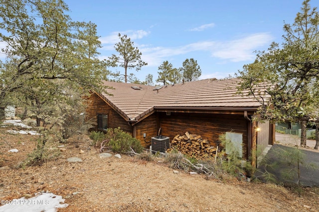 view of side of property with a tile roof and central air condition unit