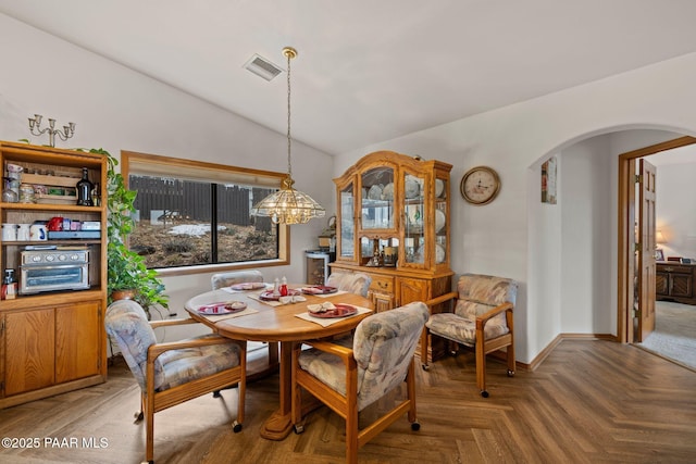 dining area with visible vents, arched walkways, a chandelier, and vaulted ceiling