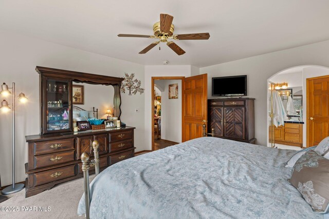carpeted bedroom featuring arched walkways and ceiling fan