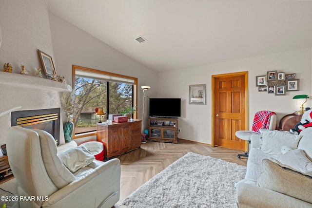 living area with visible vents, lofted ceiling, and a glass covered fireplace