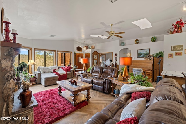living room with vaulted ceiling with skylight and a ceiling fan