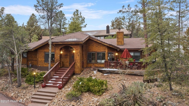 rustic home with a tiled roof and a chimney