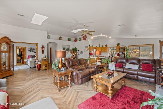 living room with arched walkways, visible vents, ceiling fan, and vaulted ceiling