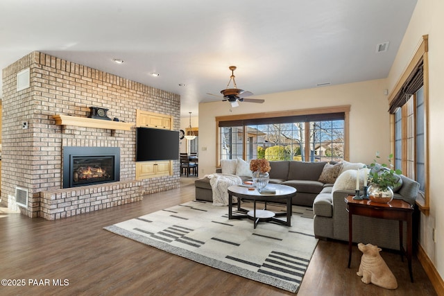 living room with dark hardwood / wood-style floors, a brick fireplace, and ceiling fan