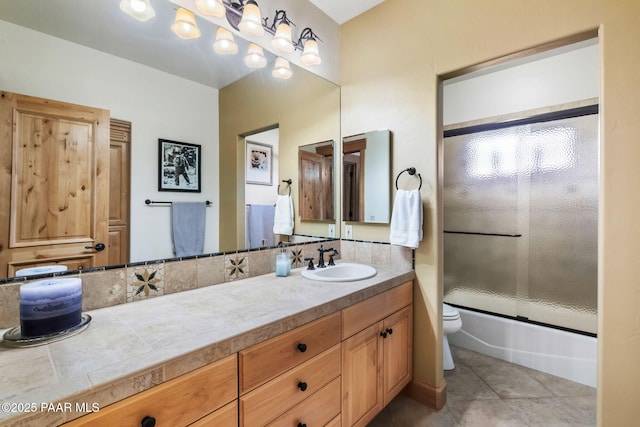 full bathroom with tile patterned floors, vanity, toilet, and shower / bath combination with glass door