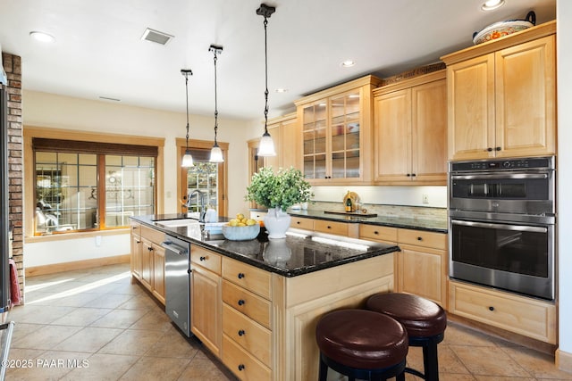 kitchen with sink, a kitchen breakfast bar, an island with sink, decorative light fixtures, and appliances with stainless steel finishes