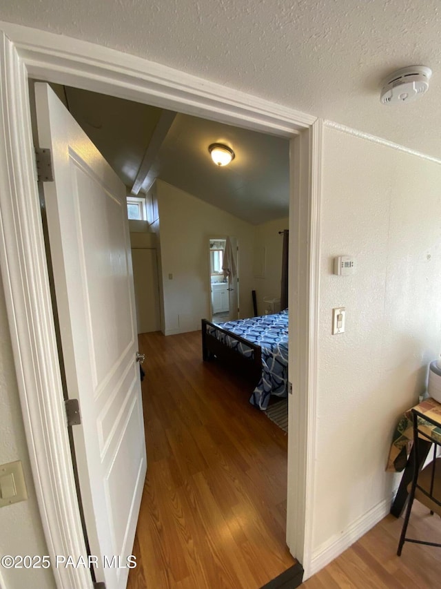 hall with vaulted ceiling and wood finished floors