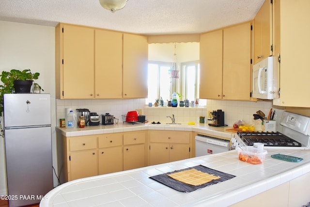 kitchen with decorative backsplash, white appliances, a textured ceiling, and cream cabinetry