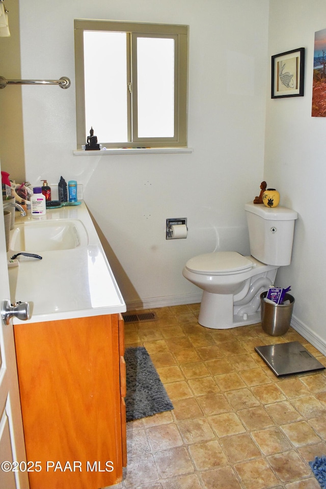 half bath featuring visible vents, toilet, tile patterned flooring, baseboards, and vanity