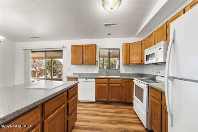 kitchen featuring plenty of natural light, white appliances, a textured ceiling, and light hardwood / wood-style flooring