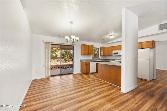 kitchen with decorative light fixtures, light wood-type flooring, white appliances, and vaulted ceiling