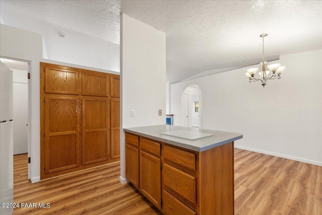 kitchen featuring light hardwood / wood-style floors, an inviting chandelier, a textured ceiling, and vaulted ceiling