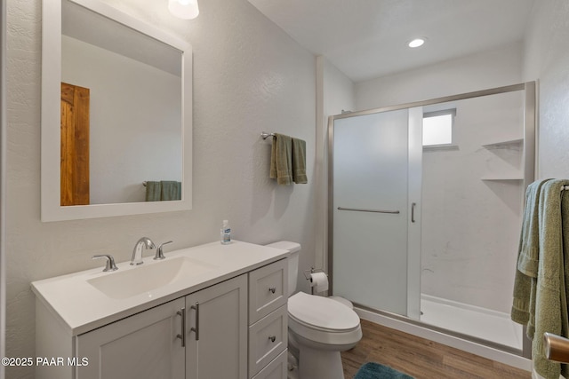 bathroom with vanity, hardwood / wood-style floors, a shower with shower door, and toilet