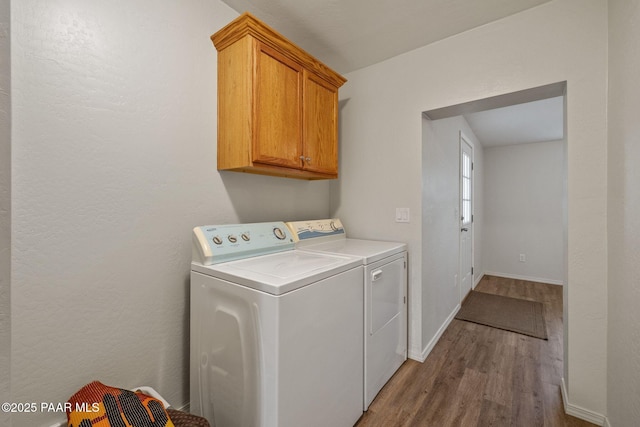 laundry area with cabinets, dark wood-type flooring, and washer and clothes dryer