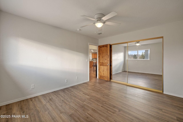 unfurnished bedroom featuring ceiling fan, wood-type flooring, and a closet