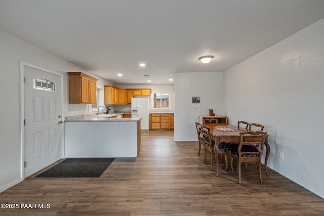 kitchen featuring sink, dark wood-type flooring, white refrigerator with ice dispenser, and kitchen peninsula