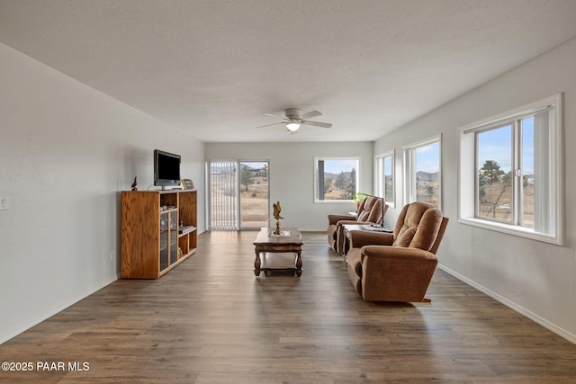 living room featuring ceiling fan, dark hardwood / wood-style floors, and a textured ceiling