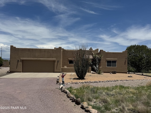 2350 W Gunsite Rd, Paulden, AZ 86334 - pueblo-style house featuring concrete driveway, an attached garage, and stucco siding