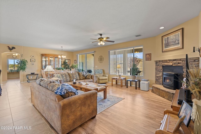 living room featuring a wood stove, light hardwood / wood-style floors, and ceiling fan with notable chandelier