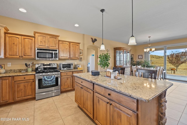 kitchen with a center island, light stone counters, decorative light fixtures, light tile patterned floors, and appliances with stainless steel finishes