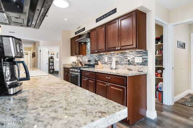 kitchen with stainless steel gas range oven, wall chimney exhaust hood, light stone countertops, tasteful backsplash, and dark hardwood / wood-style flooring