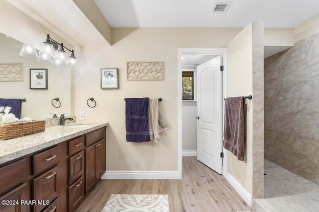 bathroom with a tile shower, vanity, and hardwood / wood-style flooring