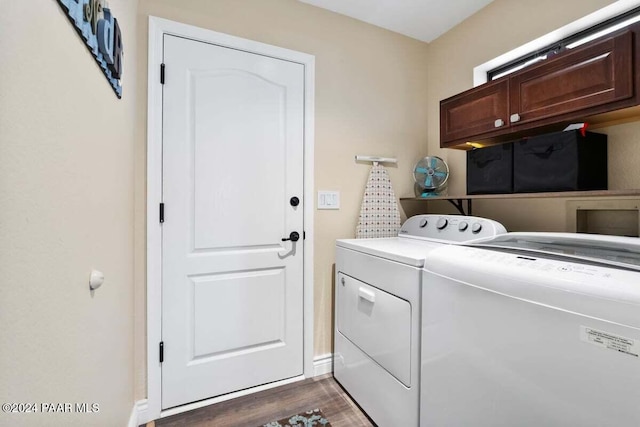 clothes washing area with washing machine and dryer, dark hardwood / wood-style flooring, and cabinets