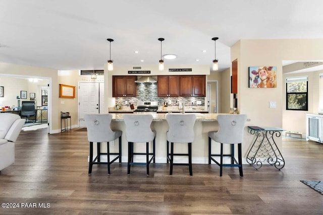 kitchen featuring radiator, light stone countertops, a breakfast bar, and pendant lighting