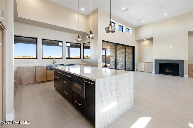 5285 High Cliff Way, Prescott, AZ 86301 - kitchen with stainless steel microwave, a kitchen island, sink, hanging light fixtures, and light stone countertops