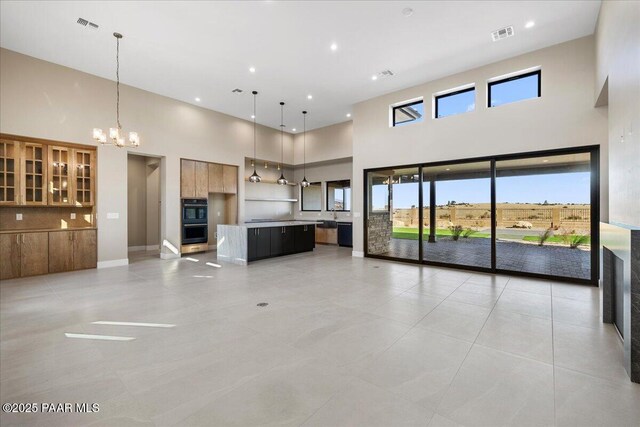 5285 High Cliff Way, Prescott, AZ 86301 - unfurnished living room featuring light tile patterned floors, an inviting chandelier, and a high ceiling