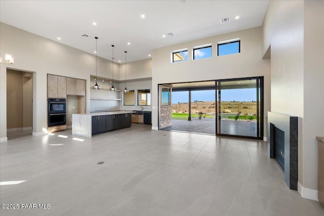 5285 High Cliff Way, Prescott, AZ 86301 - kitchen with a high ceiling, pendant lighting, double oven, light tile patterned floors, and a center island with sink