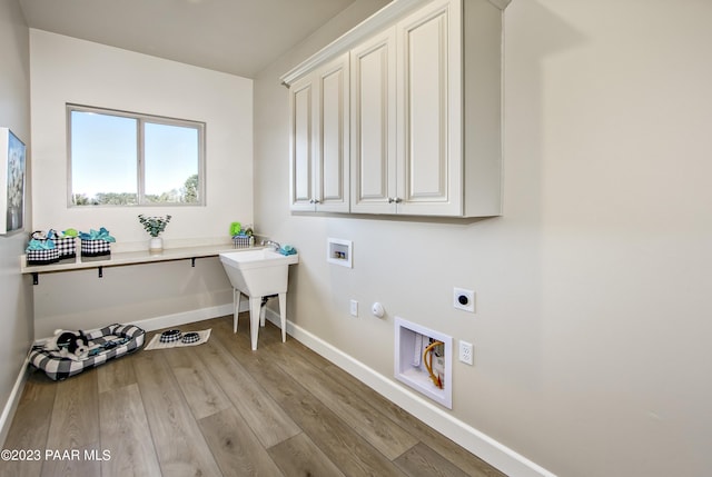 laundry room with cabinets, hookup for a washing machine, hookup for an electric dryer, light hardwood / wood-style flooring, and hookup for a gas dryer