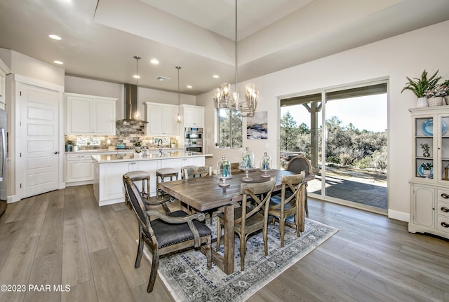 dining area with light hardwood / wood-style floors, a notable chandelier, and sink