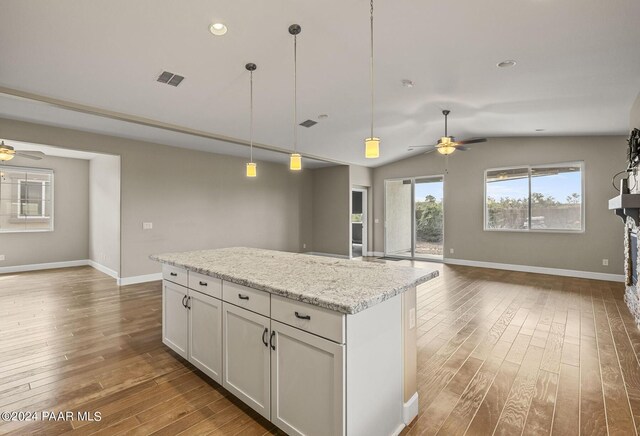 kitchen with light stone countertops, white cabinets, dark hardwood / wood-style floors, and vaulted ceiling