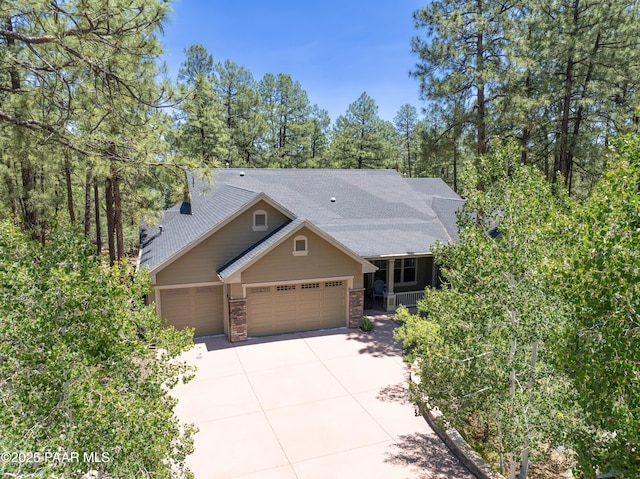 1021 Sheriffs Posse Trl, Prescott, AZ 86303 - view of front of house with concrete driveway, a garage, stone siding, roof with shingles, and covered porch