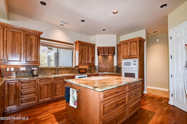 1021 Sheriffs Posse Trl, Prescott, AZ 86303 - kitchen with white appliances, light stone countertops, a kitchen island, tasteful backsplash, and dark wood finished floors