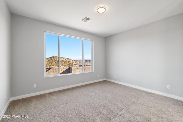 unfurnished room featuring a mountain view and carpet floors