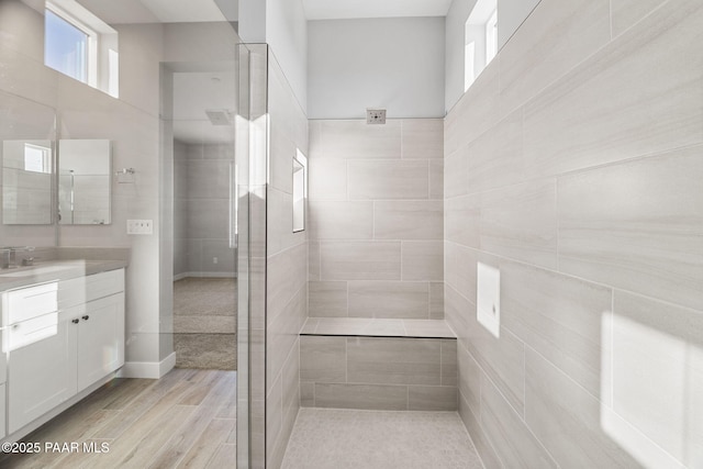 bathroom with hardwood / wood-style flooring, vanity, and a tile shower