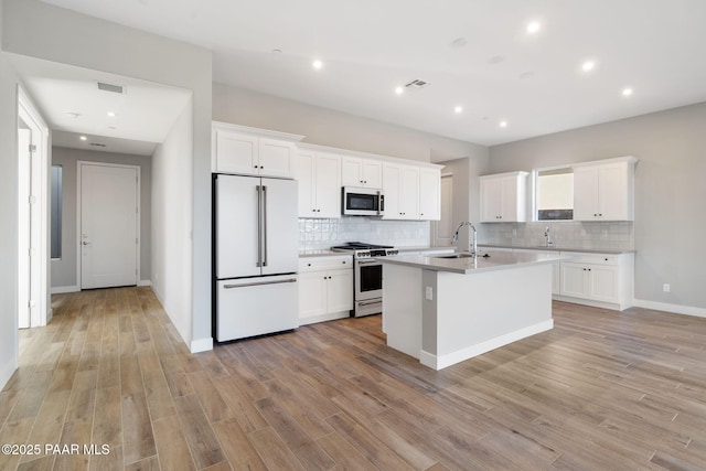 kitchen featuring white cabinetry, sink, white appliances, and an island with sink