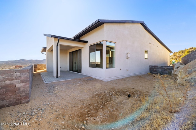 back of property with a patio and a mountain view